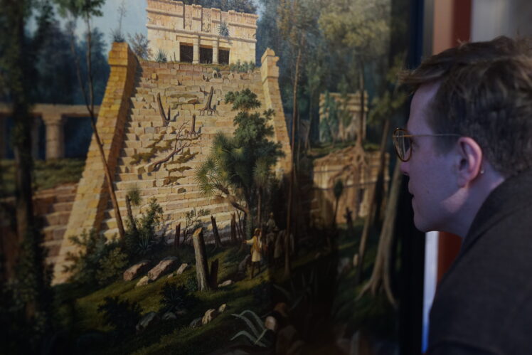 Eine Person betrachtet sehr genau das Ölgemälde Der Tempel El Castillo bei Tulum (Mexiko) von Hubert Sattler.