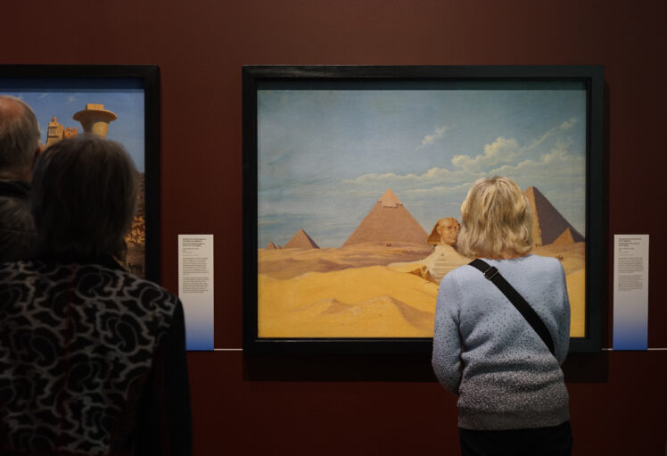 Eine Person mit hellblauem Pullover betrachtet ein Kosmorama von Hubert Sattler im Rahmen der Ausstellung Heilige Orte.