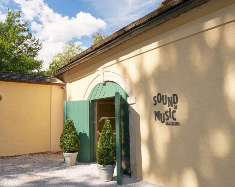 Eingang des Museums „Sound of Music Salzburg“ mit grünem Tor und Museumsschriftzug an der hellen Fassade.