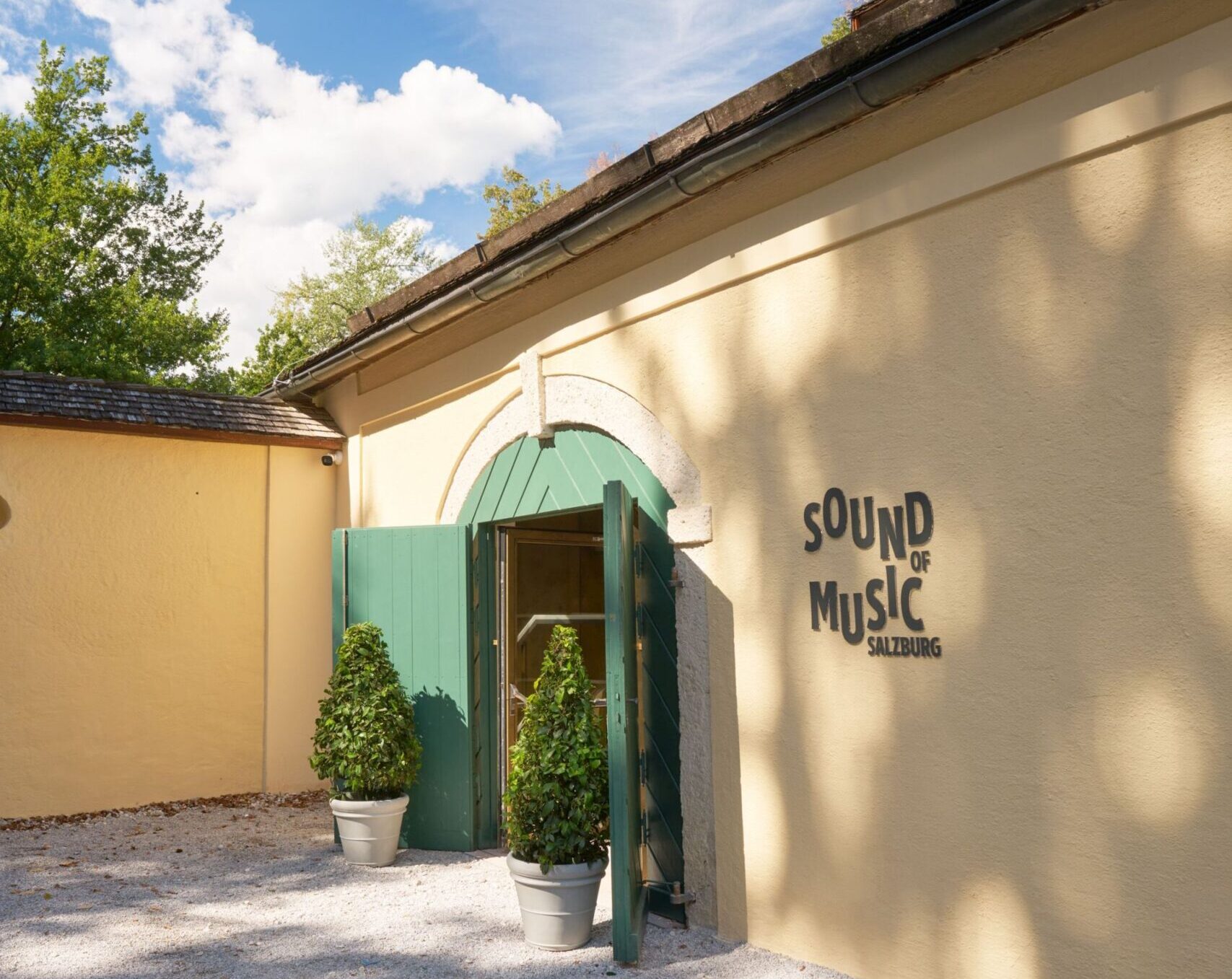 Eingang des Museums „Sound of Music Salzburg“ mit grünem Tor und Museumsschriftzug an der hellen Fassade.