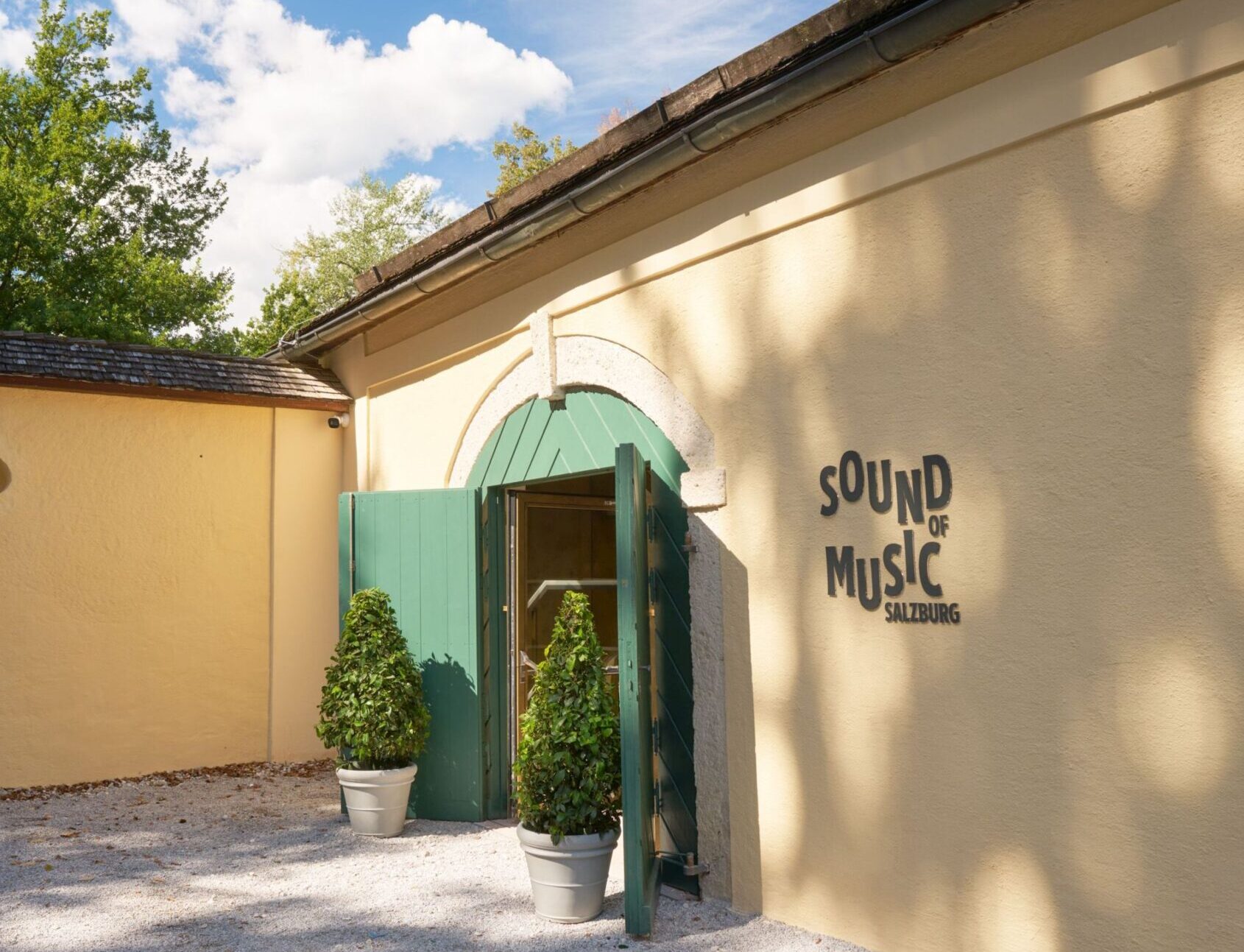 Eingang des Museums „Sound of Music Salzburg“ mit grünem Tor und Museumsschriftzug an der hellen Fassade.