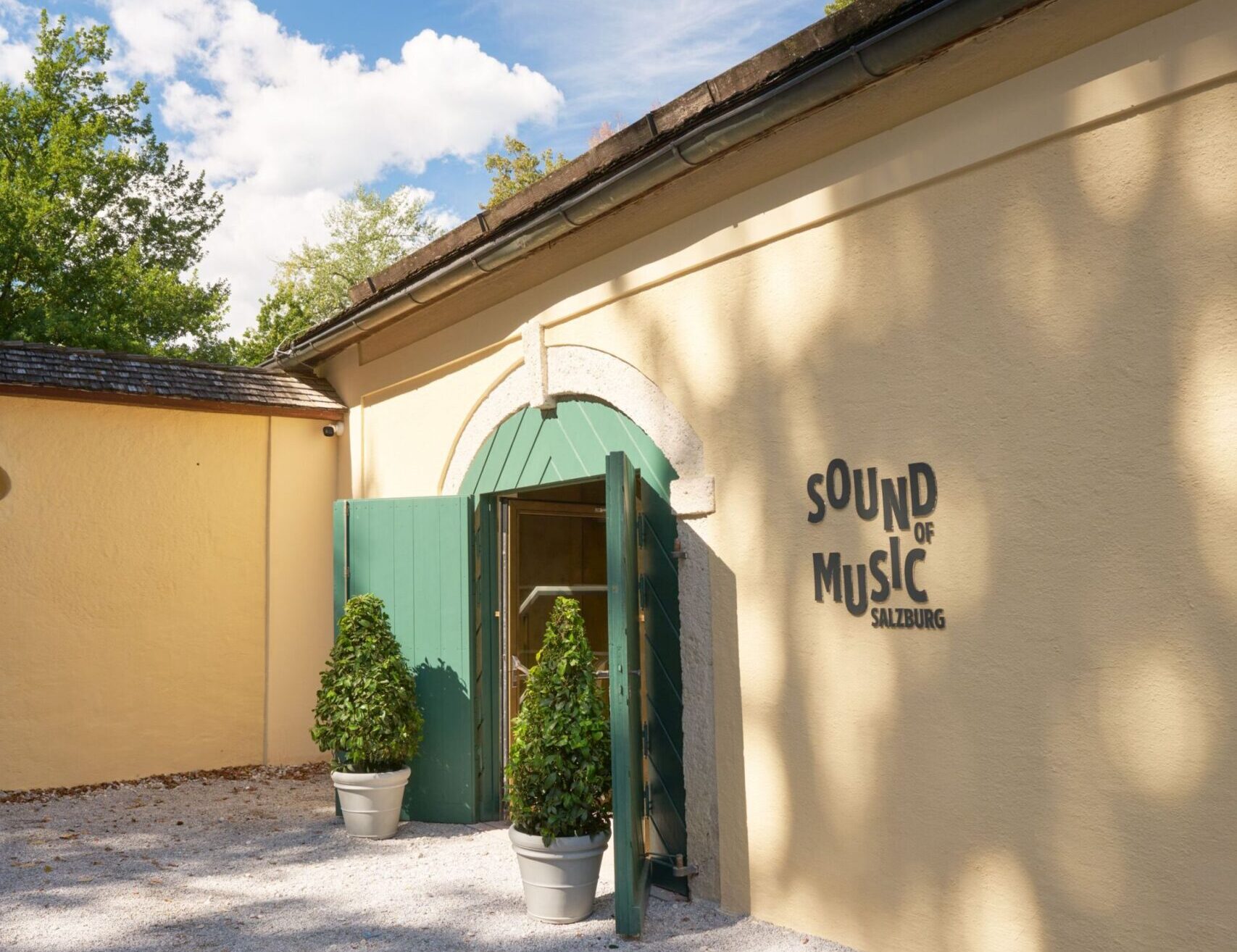 Eingang des Museums „Sound of Music Salzburg“ mit grünem Tor und Museumsschriftzug an der hellen Fassade.