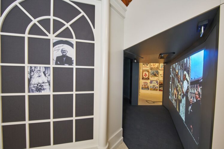 Ausstellungsbereich im „Sound of Music Salzburg“ mit historischen Fotografien, Filmprojektion und Blick auf eine Wand mit internationalen Filmplakaten.