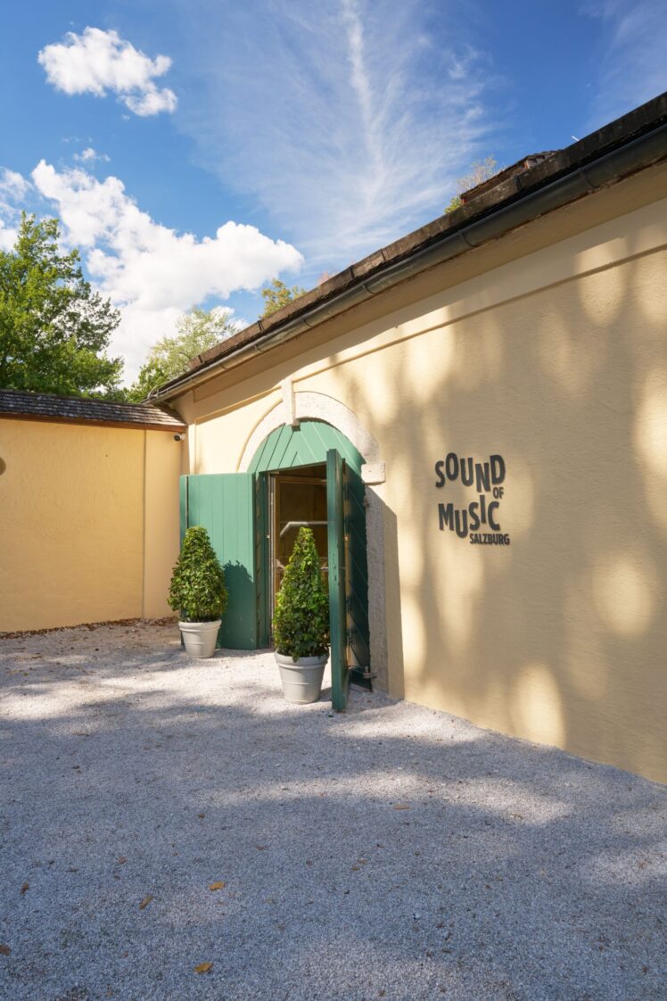 Eingang des Museums „Sound of Music Salzburg“ mit grünem Tor und Museumsschriftzug an der hellen Fassade.
